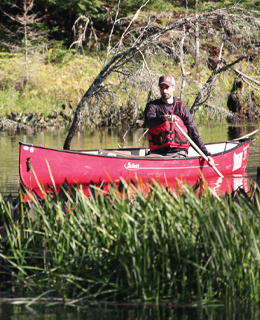 Homme pagayant dans un canot sur une rivière