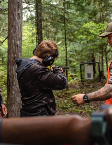 Deux hommes donnant un cours d'arme à feu à un adolescent 