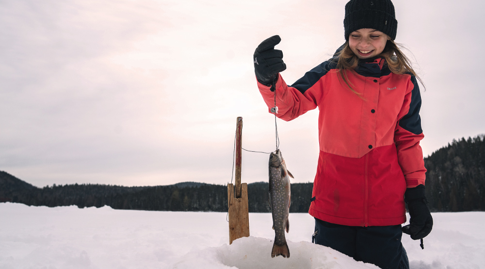 Un enfant qui pêche un poisson en hiver.