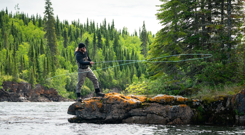 Un pêcheur à la mouche debout sur une roche